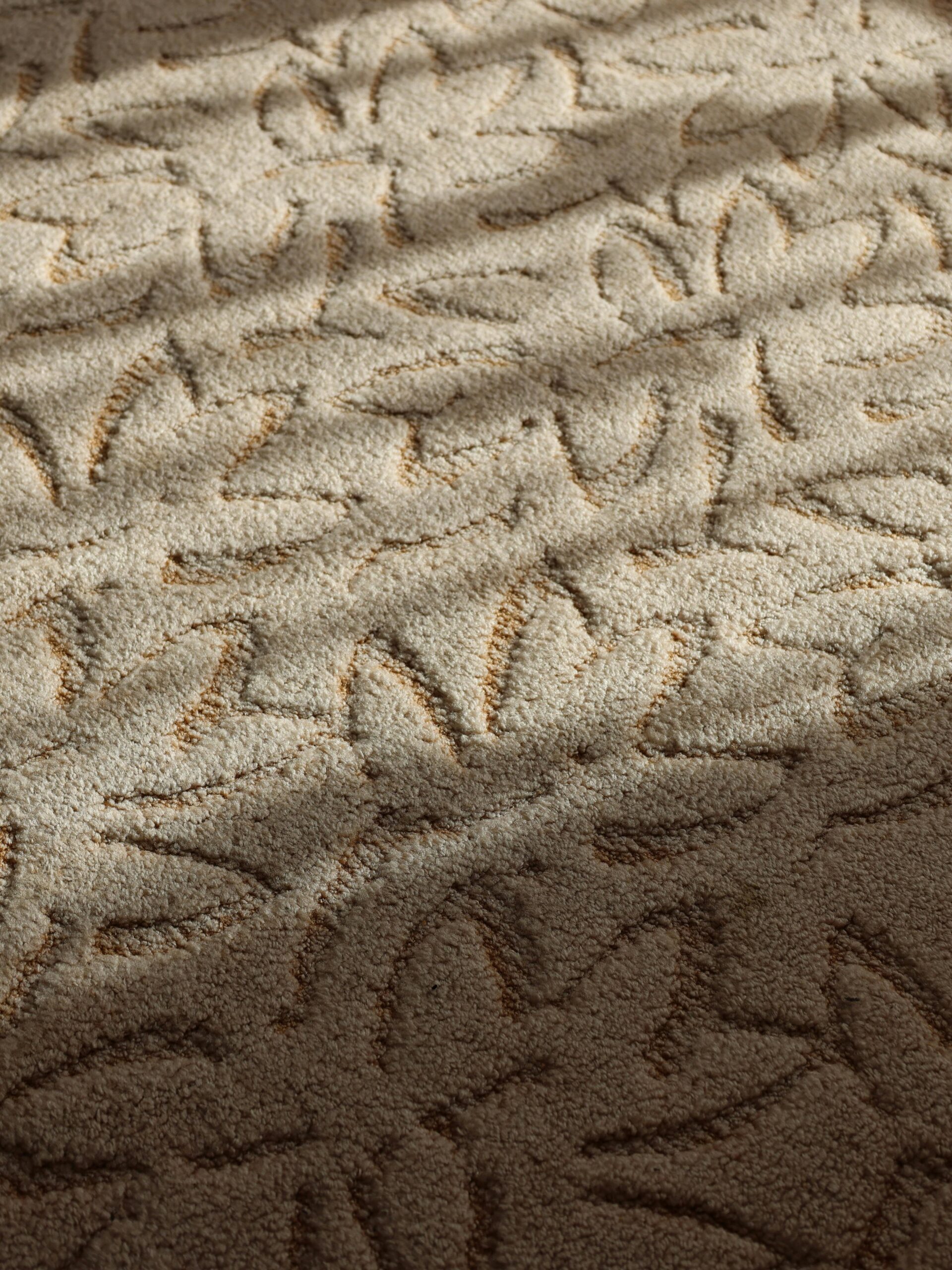 Ana Sayfa - Türkçe A close-up view of a textured beige carpet with a floral pattern under soft daylight, creating a warm and inviting atmosphere.